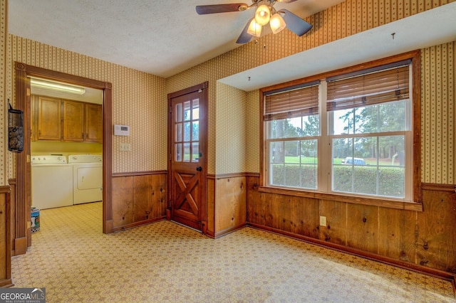 carpeted entrance foyer with ceiling fan, wooden walls, washing machine and dryer, and a textured ceiling