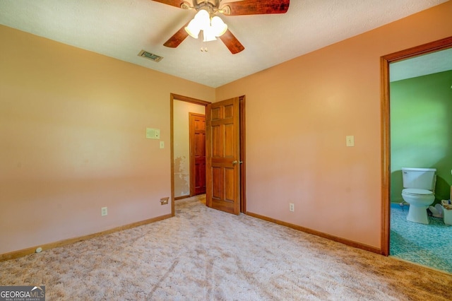 unfurnished bedroom with connected bathroom, light colored carpet, and ceiling fan