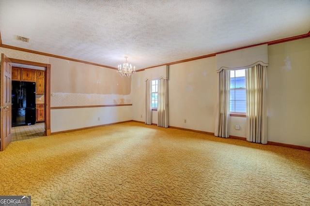 carpeted spare room featuring a notable chandelier, ornamental molding, and a textured ceiling