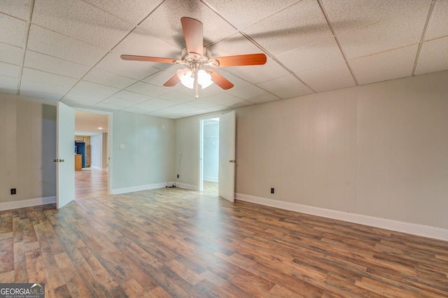 empty room featuring wood-type flooring, a drop ceiling, and ceiling fan