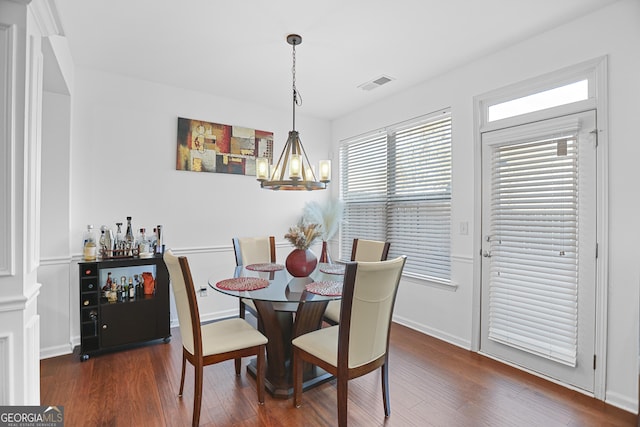 dining space with dark wood-type flooring and an inviting chandelier