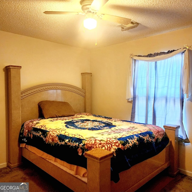 bedroom featuring ceiling fan, a textured ceiling, and dark colored carpet