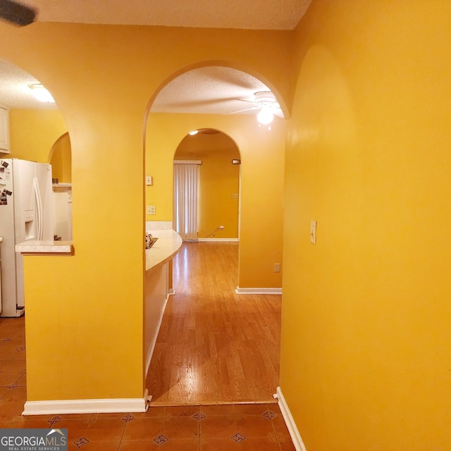 hall with a textured ceiling and tile patterned flooring