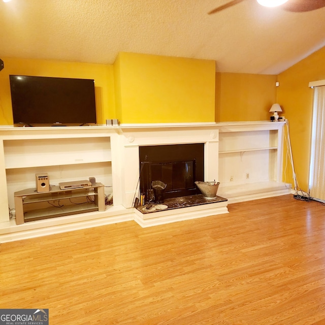 unfurnished living room with wood-type flooring, a textured ceiling, and ceiling fan