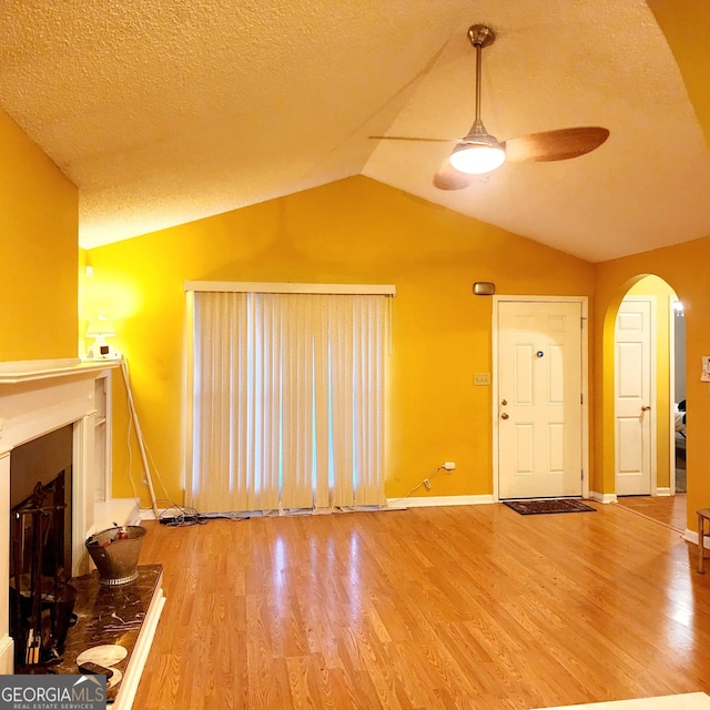 unfurnished living room with lofted ceiling, wood-type flooring, a textured ceiling, and ceiling fan