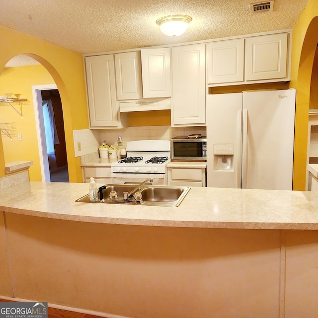 kitchen featuring backsplash, sink, white appliances, white cabinetry, and a textured ceiling