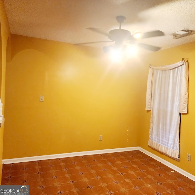 spare room featuring ceiling fan, tile patterned flooring, and a textured ceiling