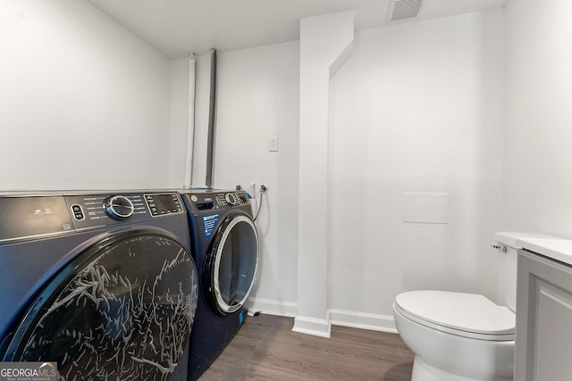 clothes washing area with dark hardwood / wood-style flooring and independent washer and dryer