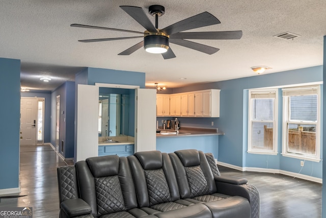 living area featuring dark wood-style flooring, visible vents, a textured ceiling, and baseboards