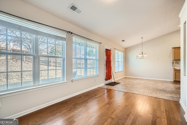 interior space with a notable chandelier, visible vents, baseboards, vaulted ceiling, and light wood finished floors