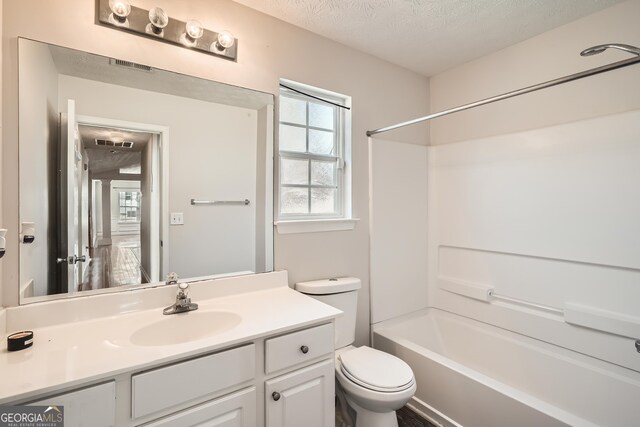 full bathroom with tub / shower combination, a textured ceiling, toilet, and vanity