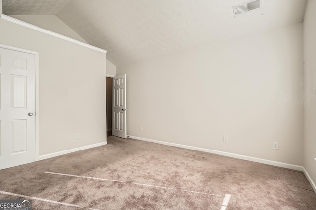 spare room featuring lofted ceiling, carpet, crown molding, and a textured ceiling