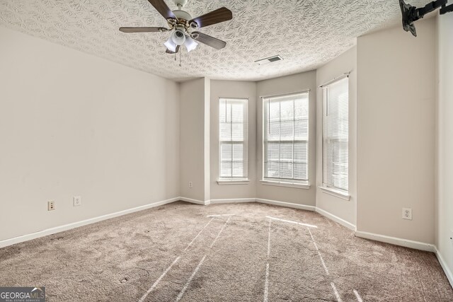 empty room featuring ceiling fan, carpet floors, and a textured ceiling