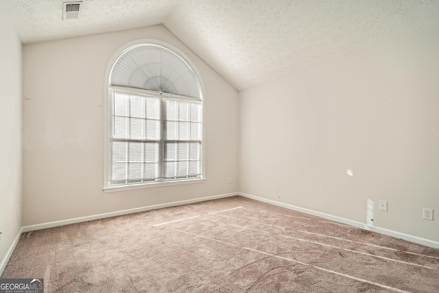 carpeted spare room featuring lofted ceiling, a textured ceiling, visible vents, and baseboards