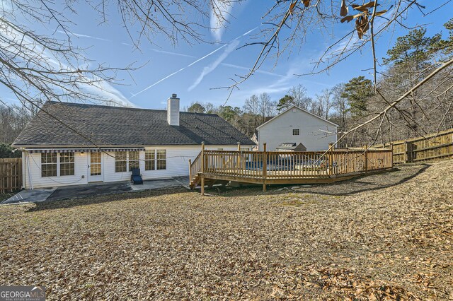 rear view of property featuring a wooden deck and a patio