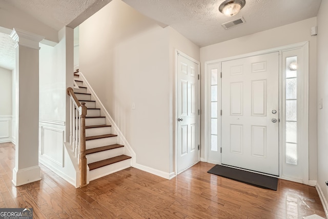 foyer with plenty of natural light, a textured ceiling, and light wood-type flooring