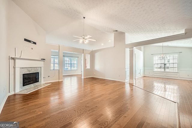 unfurnished living room with ceiling fan with notable chandelier, a textured ceiling, hardwood / wood-style floors, and a fireplace