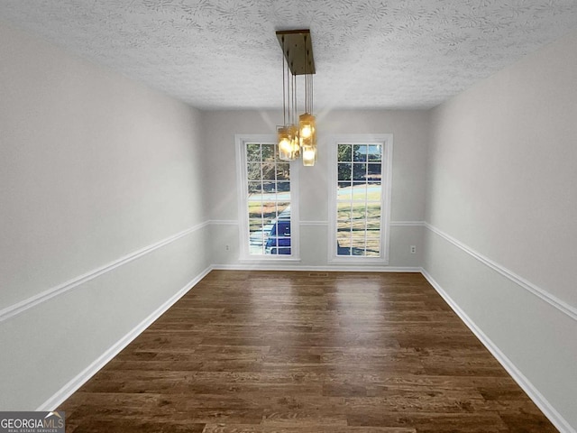 unfurnished dining area featuring dark hardwood / wood-style floors and a textured ceiling