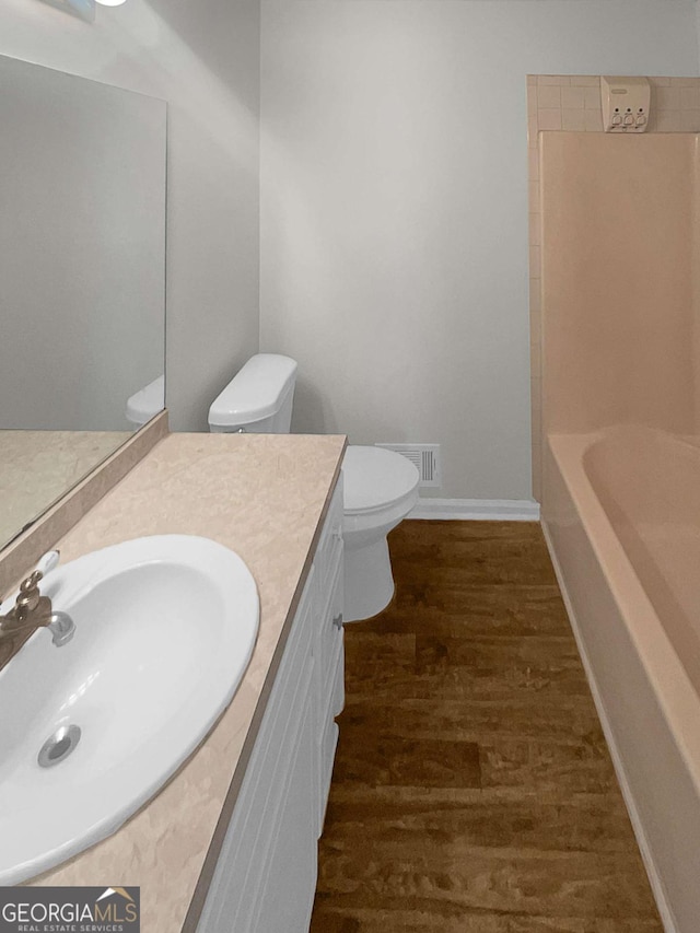 bathroom with hardwood / wood-style flooring, toilet, and vanity