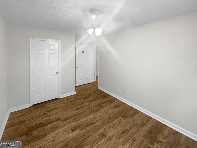 bonus room with ceiling fan, dark wood-type flooring, and a textured ceiling