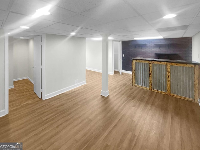 basement featuring a drop ceiling and wood-type flooring