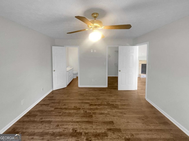 unfurnished bedroom with ceiling fan, connected bathroom, dark hardwood / wood-style flooring, and a textured ceiling