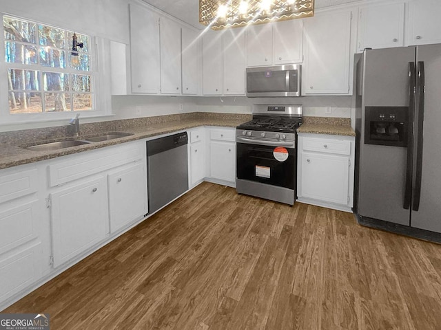 kitchen with sink, white cabinets, appliances with stainless steel finishes, and hardwood / wood-style floors