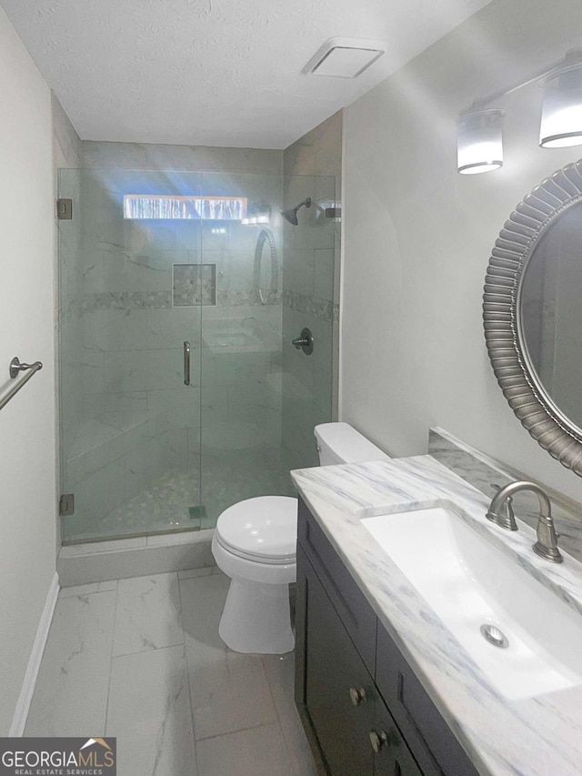 bathroom featuring toilet, vanity, walk in shower, and a textured ceiling