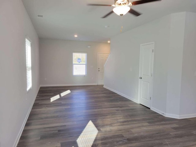 empty room with ceiling fan, a healthy amount of sunlight, and dark hardwood / wood-style flooring