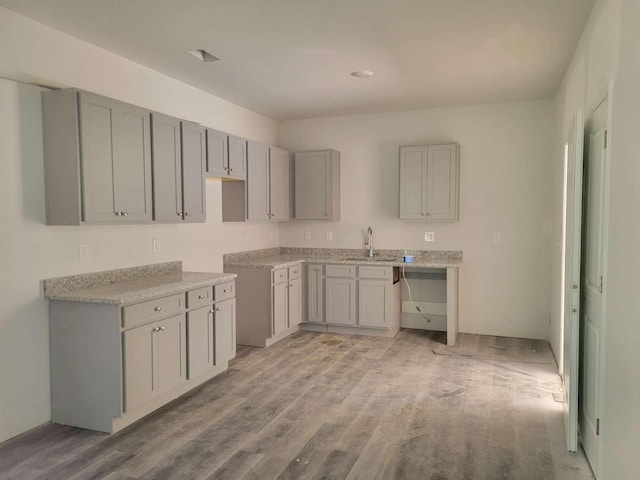 kitchen with gray cabinets, sink, and light hardwood / wood-style floors