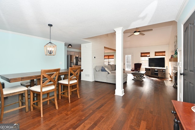 dining space with ceiling fan with notable chandelier, dark wood-type flooring, and a textured ceiling