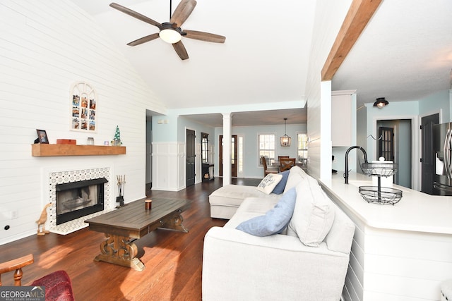 living room featuring ceiling fan, a tiled fireplace, dark hardwood / wood-style flooring, and high vaulted ceiling