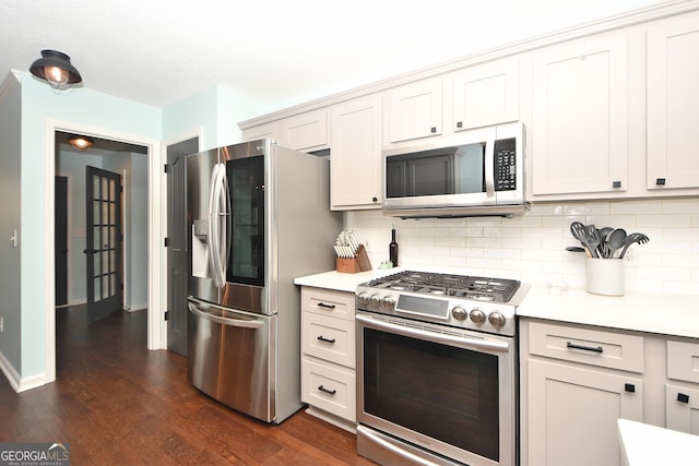 kitchen with dark wood-type flooring, white cabinetry, appliances with stainless steel finishes, and tasteful backsplash