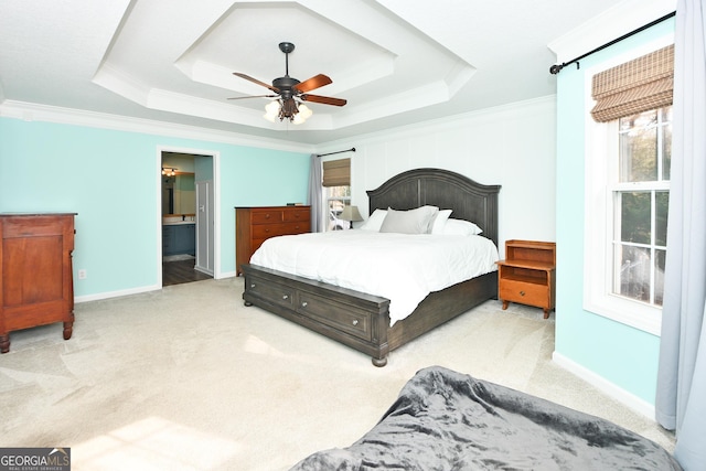 carpeted bedroom featuring ceiling fan, ornamental molding, a tray ceiling, and ensuite bath