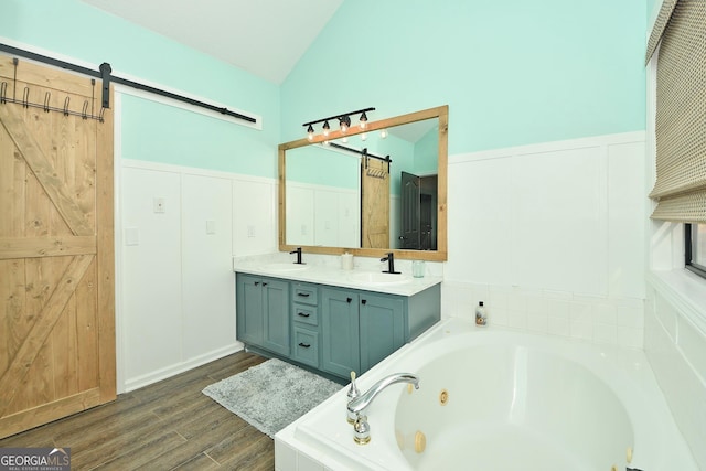 bathroom featuring vanity, lofted ceiling, hardwood / wood-style flooring, and a relaxing tiled tub