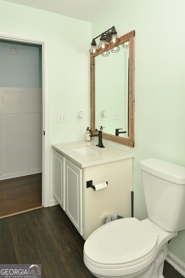 bathroom with toilet, hardwood / wood-style flooring, and vanity