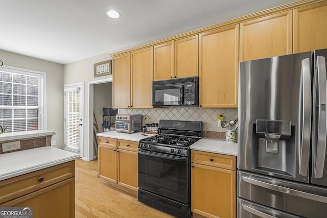 kitchen featuring tasteful backsplash, light brown cabinetry, light hardwood / wood-style floors, and black appliances