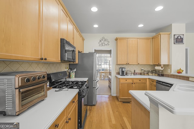 kitchen featuring black appliances, sink, backsplash, kitchen peninsula, and light hardwood / wood-style flooring