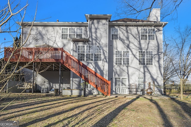 rear view of property featuring a lawn and a deck