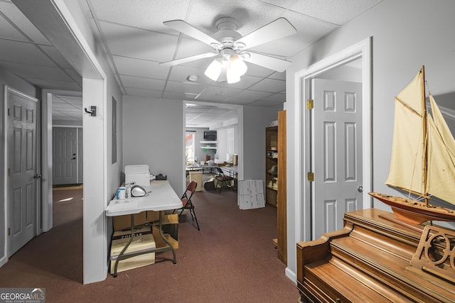 interior space with ceiling fan, a paneled ceiling, and carpet flooring