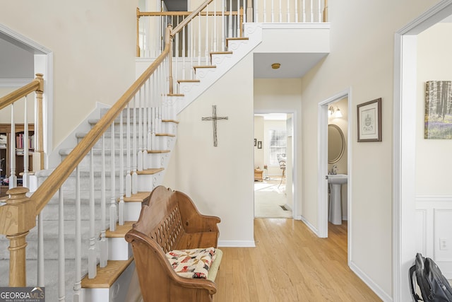 staircase featuring a high ceiling, wood-type flooring, and sink