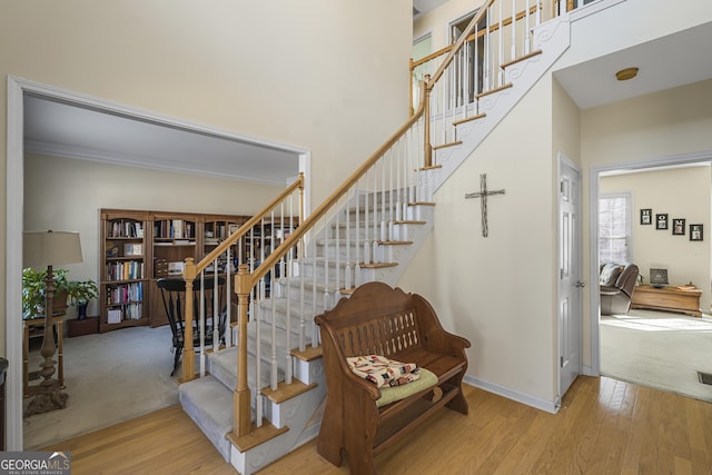 stairway with ornamental molding, wood-type flooring, and a high ceiling