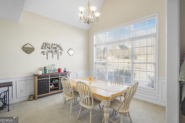 dining area featuring light carpet, vaulted ceiling, a healthy amount of sunlight, and an inviting chandelier