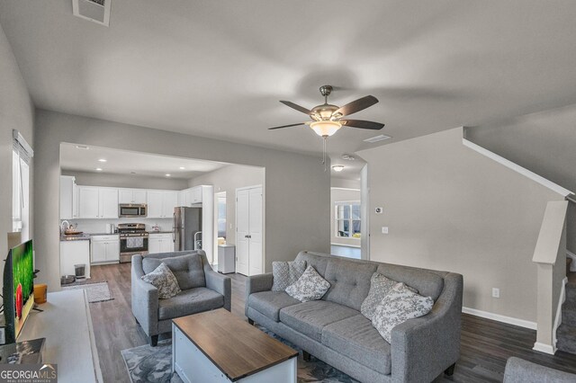 living room with a healthy amount of sunlight, dark wood-type flooring, and ceiling fan