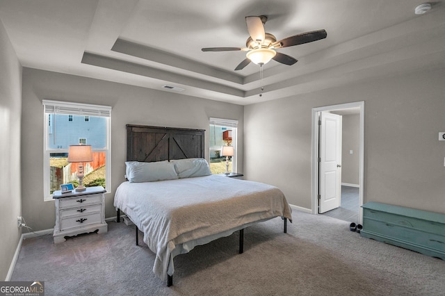 bedroom featuring ceiling fan, a raised ceiling, and carpet