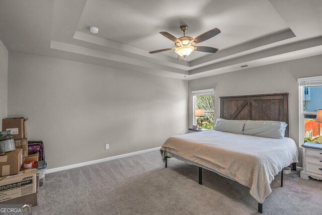 carpeted bedroom featuring ceiling fan and a tray ceiling