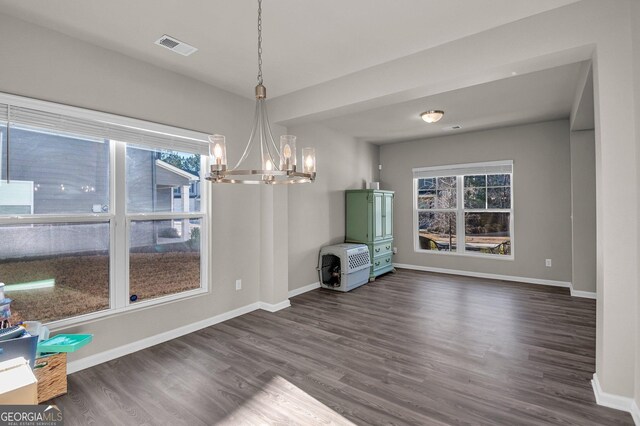 unfurnished dining area featuring dark hardwood / wood-style floors and a chandelier