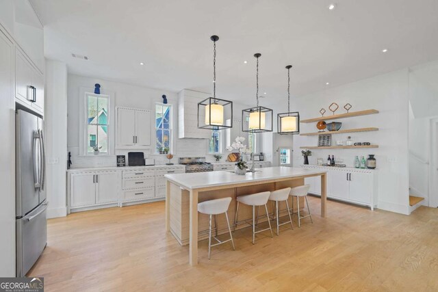 kitchen featuring appliances with stainless steel finishes, white cabinetry, a kitchen bar, and a center island