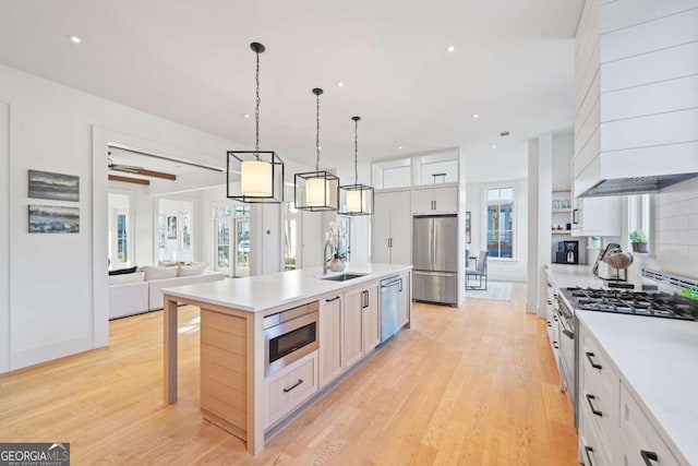 kitchen featuring backsplash, light wood-style flooring, stainless steel appliances, and a sink