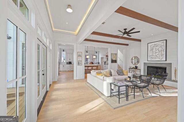 living room featuring ceiling fan, light hardwood / wood-style floors, french doors, and beamed ceiling